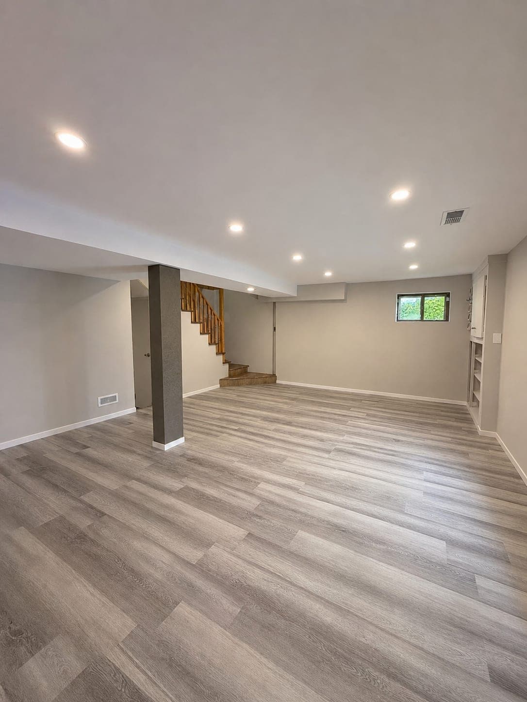 Finished basement with new plank flooring, painted walls, and recessed lighting, after Renovision AnA's renovation
